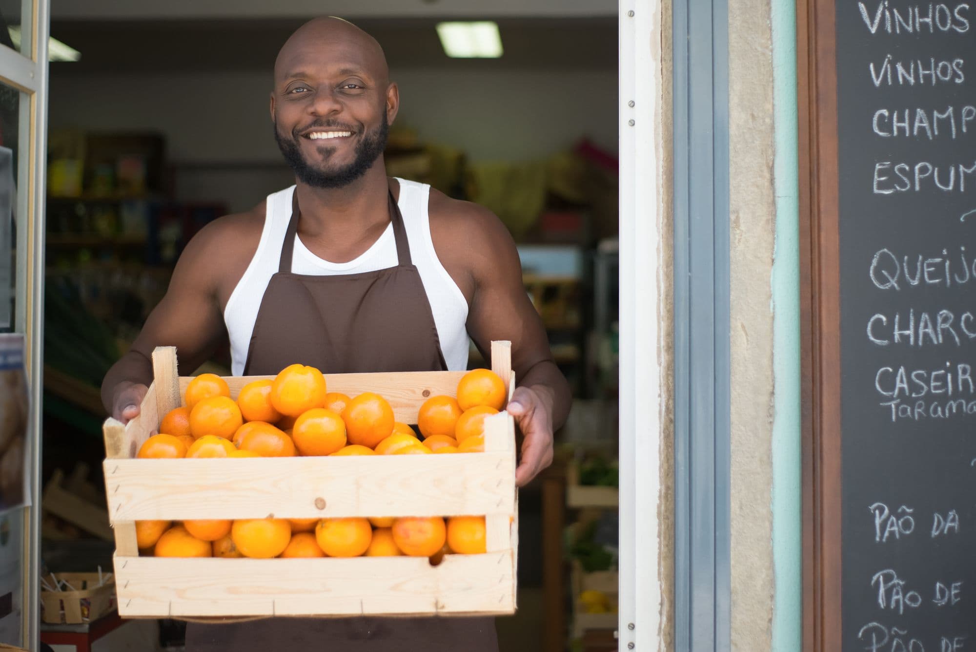 A market trader carrying a crate of produce into his stall