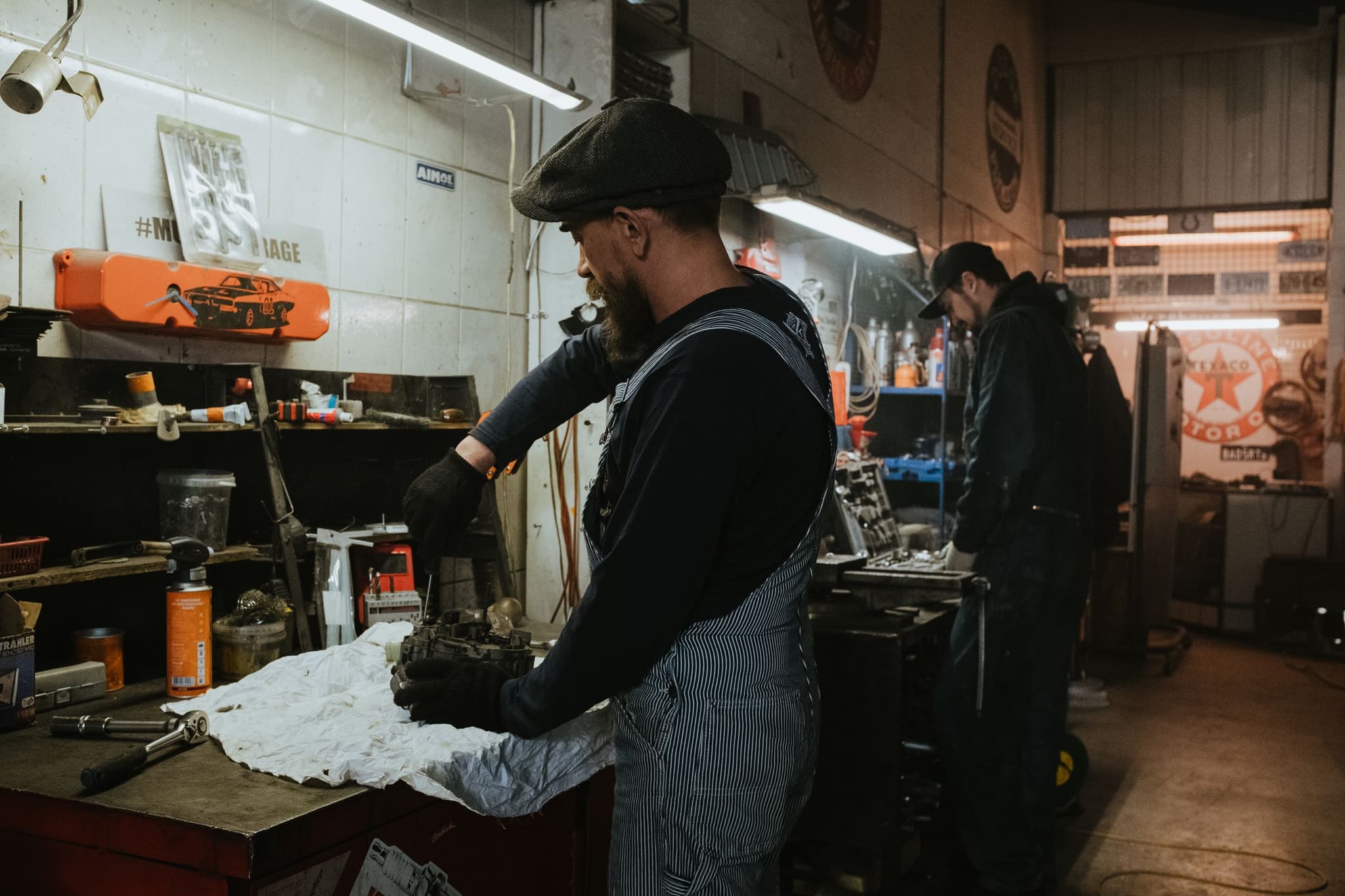 Two mechanics at work in a small independent garage, mid-job at the bench